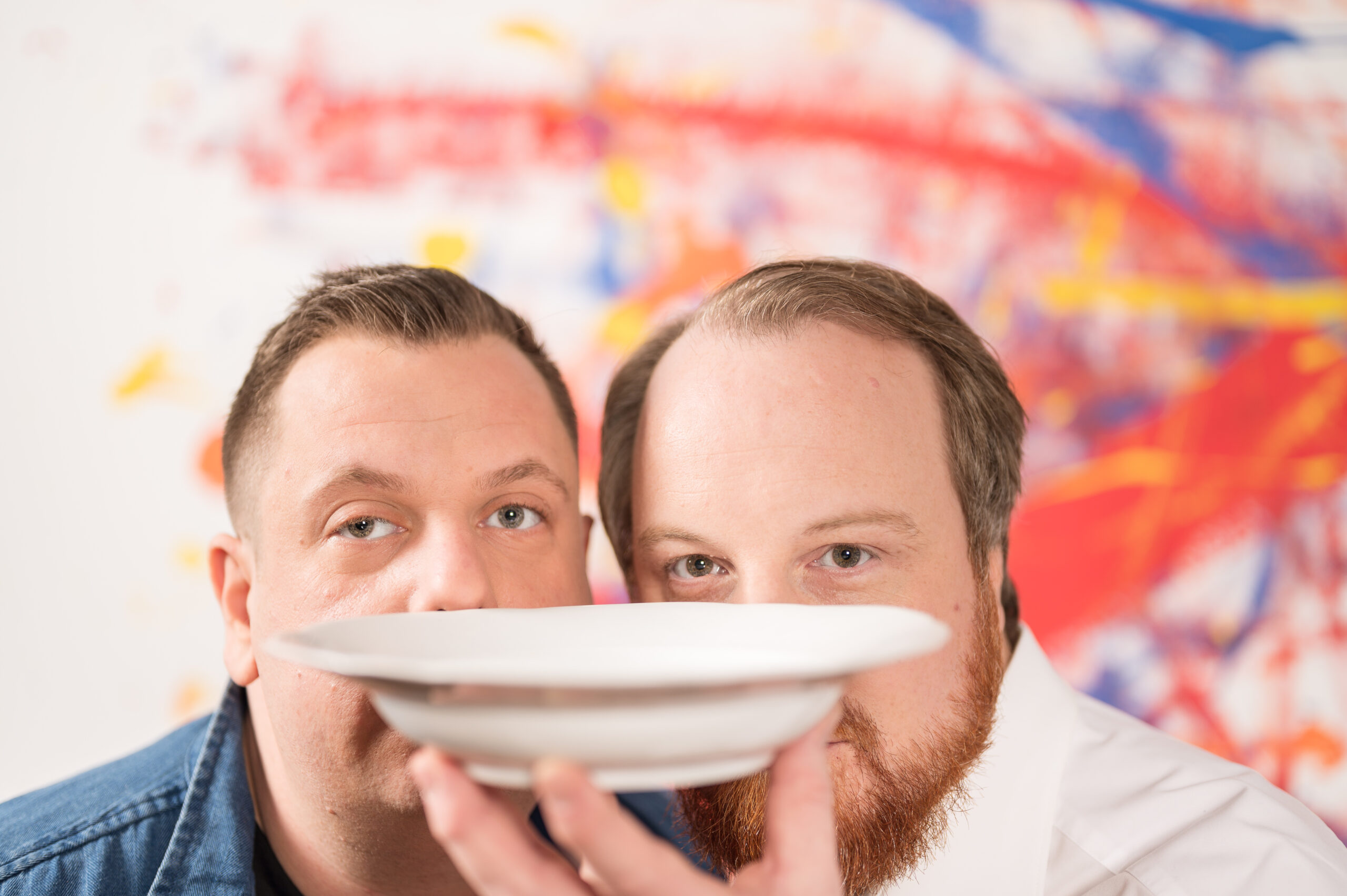 Tobias Weber und Fabian Daheim von format:c live communication GmbH schauen über den Tellerrand eines weißen Tellers hinaus.